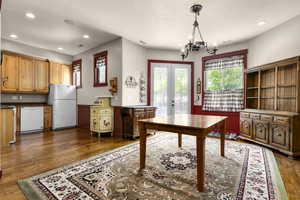 Office area with a chandelier, recessed lighting, dark wood finished floors, a wainscoted wall, and french doors