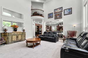Carpeted living room with a towering ceiling, crown molding, healthy amount of natural light, and baseboards