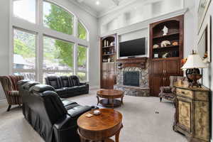 Carpeted living room with ornamental molding, a fireplace, a towering ceiling, beamed ceiling, and coffered ceiling