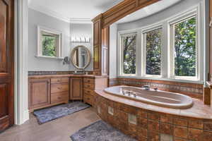 Full bath with plenty of natural light, vanity, a bath, and ornamental molding