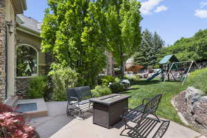 View of patio featuring a playground and an outdoor fire pit