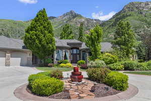 French country inspired facade with stone siding, a garage, a mountain view, and concrete driveway