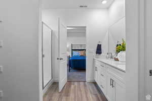 Ensuite bathroom with double vanity, wood finished floors, a shower stall, and baseboards