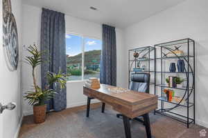 Carpeted home office featuring baseboards