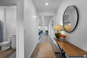Hall with wood finished floors, recessed lighting, and baseboards