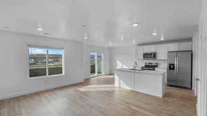 Kitchen featuring appliances with stainless steel finishes, a sink, light wood-style flooring, baseboards, and recessed lighting