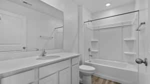 Bathroom featuring wood finished floors, vanity, shower / bath combination, and toilet