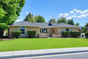 Ranch-style house with a front lawn, a chimney, and brick siding