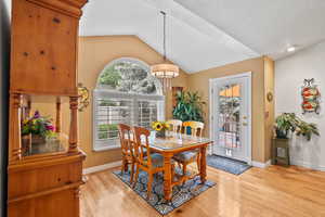 Dining area featuring vaulted ceiling, light wood finished floors, baseboards, and a chandelier