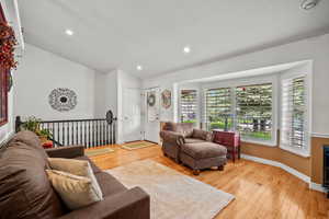 Living area with lofted ceiling, light wood finished floors, baseboards, and recessed lighting