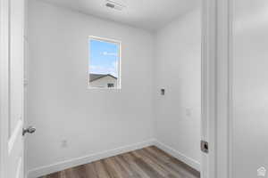 Laundry area with wood finished floors, baseboards, and hookup for a washing machine