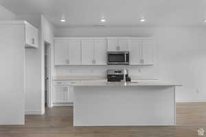 Kitchen featuring appliances with stainless steel finishes, a sink, light countertops, light wood-style floors, and recessed lighting