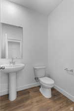 Bathroom with baseboards, toilet, wood finished floors, and a sink