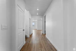 Corridor with recessed lighting, wood finished floors, and baseboards