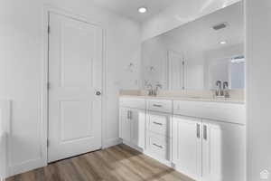 Bathroom with double vanity, wood finished floors, and recessed lighting