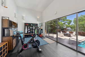 Workout room with high vaulted ceiling and wood finished floors