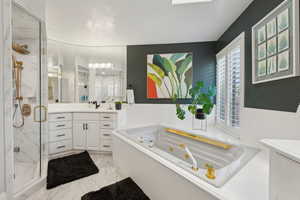 Bathroom with a stall shower, vanity, a tub with jets, and marble look tiles
