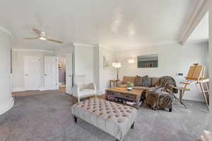 Living room with carpet, a ceiling fan, baseboards, and crown molding