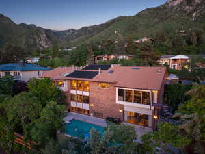 Rear view of house featuring stairway, a mountain view, an outdoor pool, and brick siding