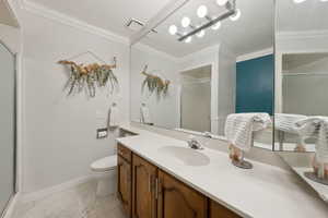 Bathroom with a shower stall, ornamental molding, vanity, toilet, and baseboards