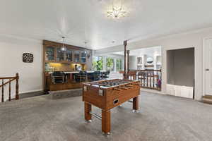 Recreation room with carpet, ornamental molding, and baseboards
