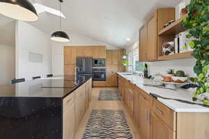 Kitchen with black appliances, open shelves, a sink, vaulted ceiling, and a spacious island