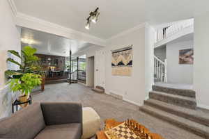 Living room with carpet floors, stairway, crown molding, and baseboards