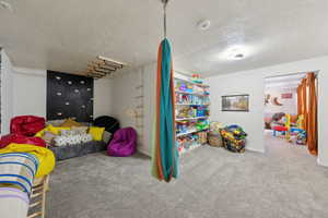Playroom featuring carpet flooring, a textured ceiling, and baseboards