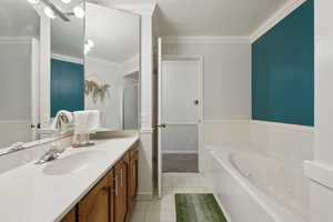 Bathroom with tile patterned floors, a jetted tub, vanity, crown molding, and baseboards