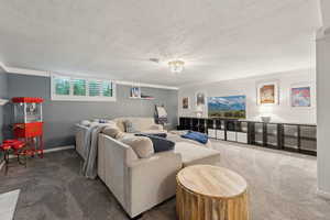 Carpeted living room with a textured ceiling and baseboards