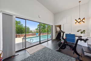 Workout area with healthy amount of natural light, a towering ceiling, wood finished floors, and a chandelier