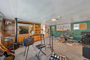 Recreation room featuring carpet, a textured ceiling, and baseboards