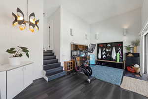 Exercise room featuring dark wood-style floors, a chandelier, and a towering ceiling