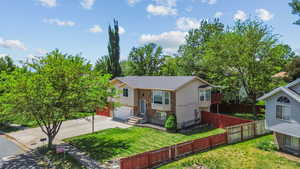 Raised ranch featuring driveway, an attached garage, and brick siding