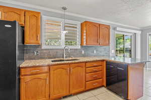 Kitchen featuring a sink, black appliances, light tile patterned flooring, decorative backsplash, and crown molding