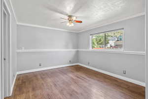 Spare room with a ceiling fan, wood finished floors, baseboards, a textured ceiling, and crown molding