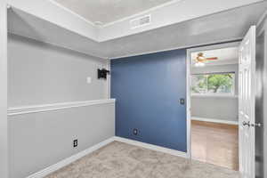 Spare room featuring a textured ceiling, baseboards, carpet flooring, ceiling fan, and ornamental molding