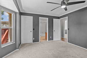 Unfurnished bedroom featuring a textured ceiling, carpet flooring, baseboards, ensuite bath, and ceiling fan