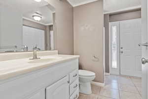 Bathroom featuring vanity, tile patterned floors, toilet, baseboards, and ornamental molding
