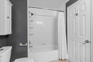 Bathroom with toilet, shower / bath combo, and tile patterned floors