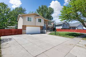 Split foyer home featuring brick siding, an attached garage, and concrete driveway