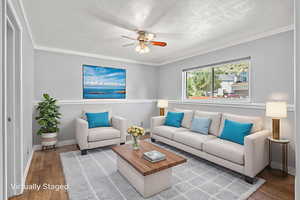 virtually staged Living room featuring a ceiling fan, wood finished floors, baseboards, and ornamental molding