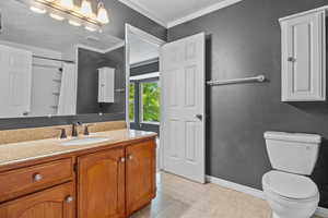 Bathroom with vanity, toilet, tile patterned floors, ornamental molding, and a shower with curtain