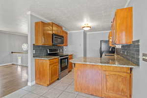 Kitchen with black appliances, a sink, tasteful backsplash, a peninsula, and light tile patterned floors