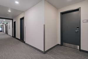 Corridor with dark wood-style flooring, baseboards, and recessed lighting
