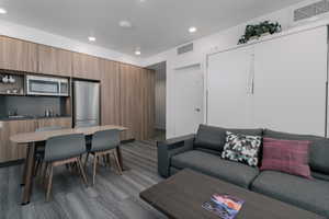 Living area with dark wood finished floors, recessed lighting, and bar area