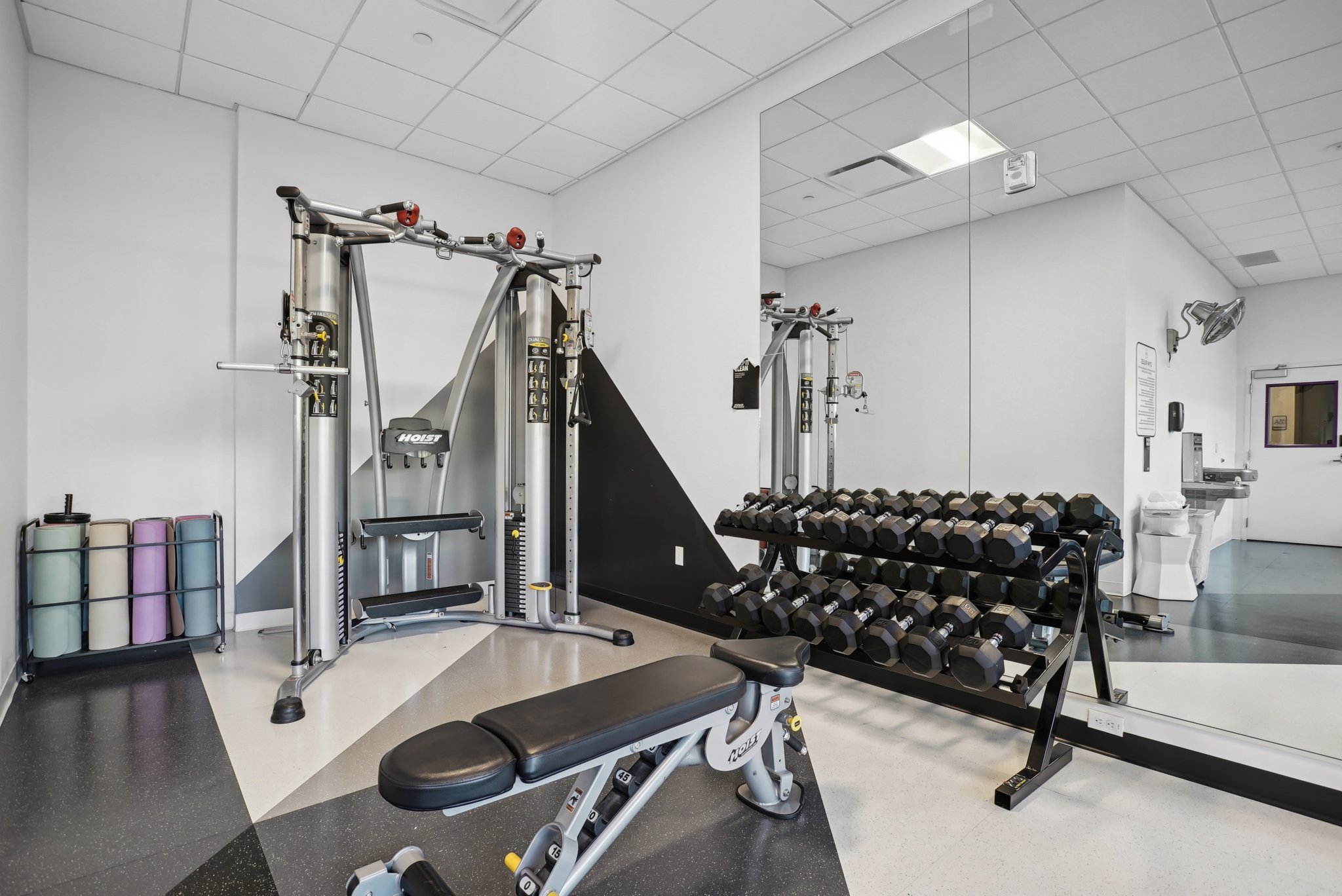 Gym with a paneled ceiling and baseboards