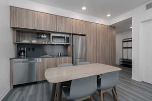 Kitchen featuring stainless steel appliances, dark wood-type flooring, baseboards, a sink, and modern cabinets