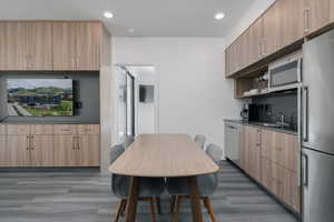 Kitchen featuring appliances with stainless steel finishes, a sink, dark wood-style floors, dark countertops, and light brown cabinets