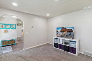 Unfurnished living room with arched walkways, carpet, baseboards, and recessed lighting